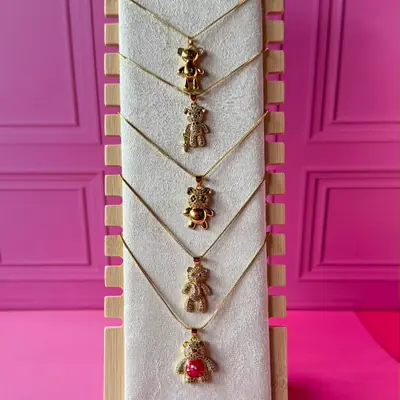 Collares dorados con distintos dijes de oso, uno con piedra roja