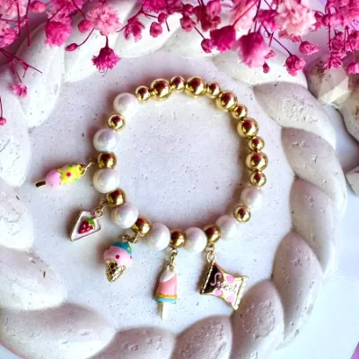 Pulsera encauchada en polvo de nacar con dijes en rodio y balines #6 y #8 en rodio