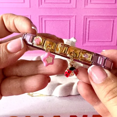 Pulsera en acero elástica pulso en color rosado y dijes en color dorado de estrella de mar,dije colgante de estrella rosada, dije de helado con cristales, dije colgante de mariquita, dije de caramelo con cristal rosado. 5 charms