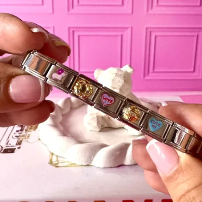Pulsera en acero elástica y pulso color plateado. Dije de corazon azul, dije de dona,dije de paisaje, dije de cupcake, dije de cabrita rosa. 5 charms.