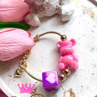 Pulsera en rodio tipo pandora, oso en resina y cubo tono lila con rosa en acrílico.